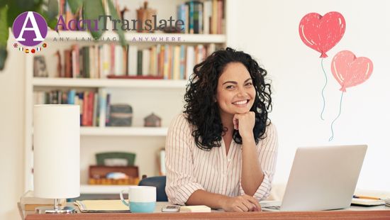 A woman with long curly dark hair in front of a laptop with two heart-shaped ballons attached to the top of it.